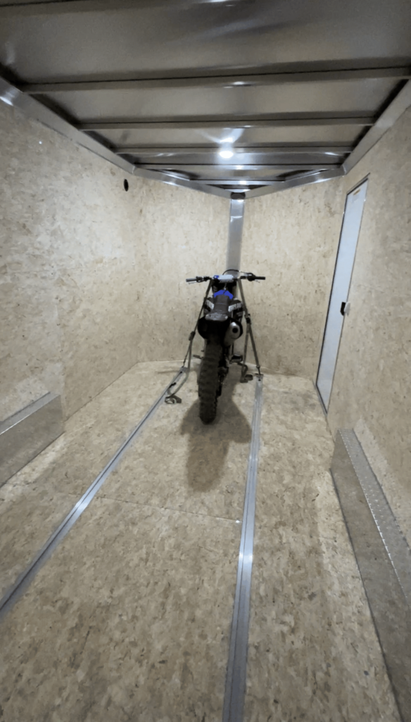 Inside an enclosed trailer with a dirt bike tied down inside