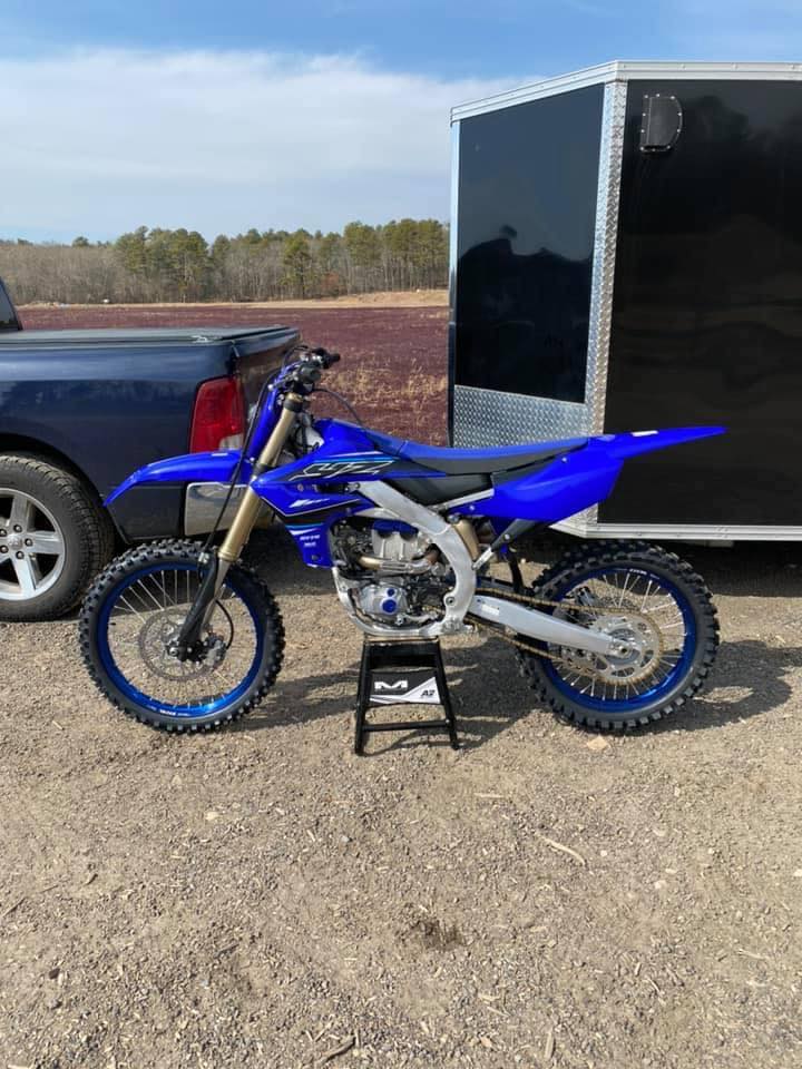 Yamaha YZ250F on black stand in front of pickup truck and trailer