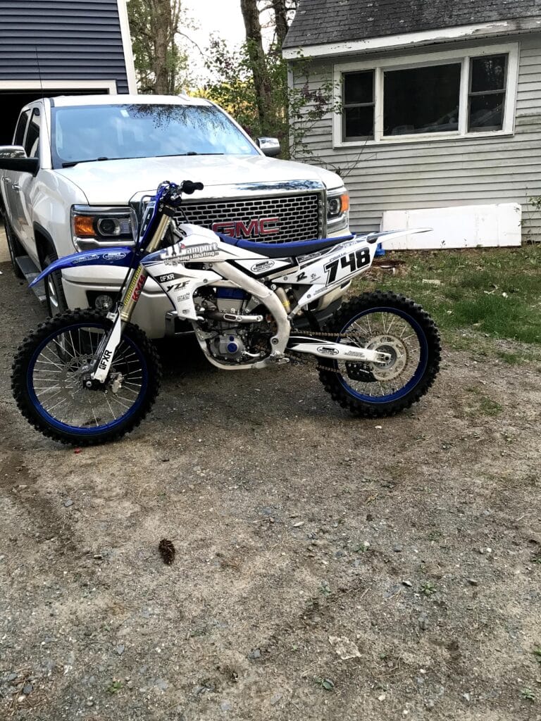 Yamaha YZ450F leaning against a white pickup truck